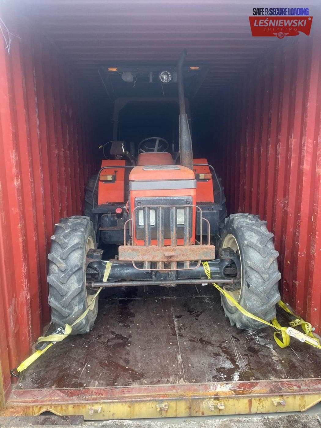 Red farm tractor secured in a container — agricultural machinery transport