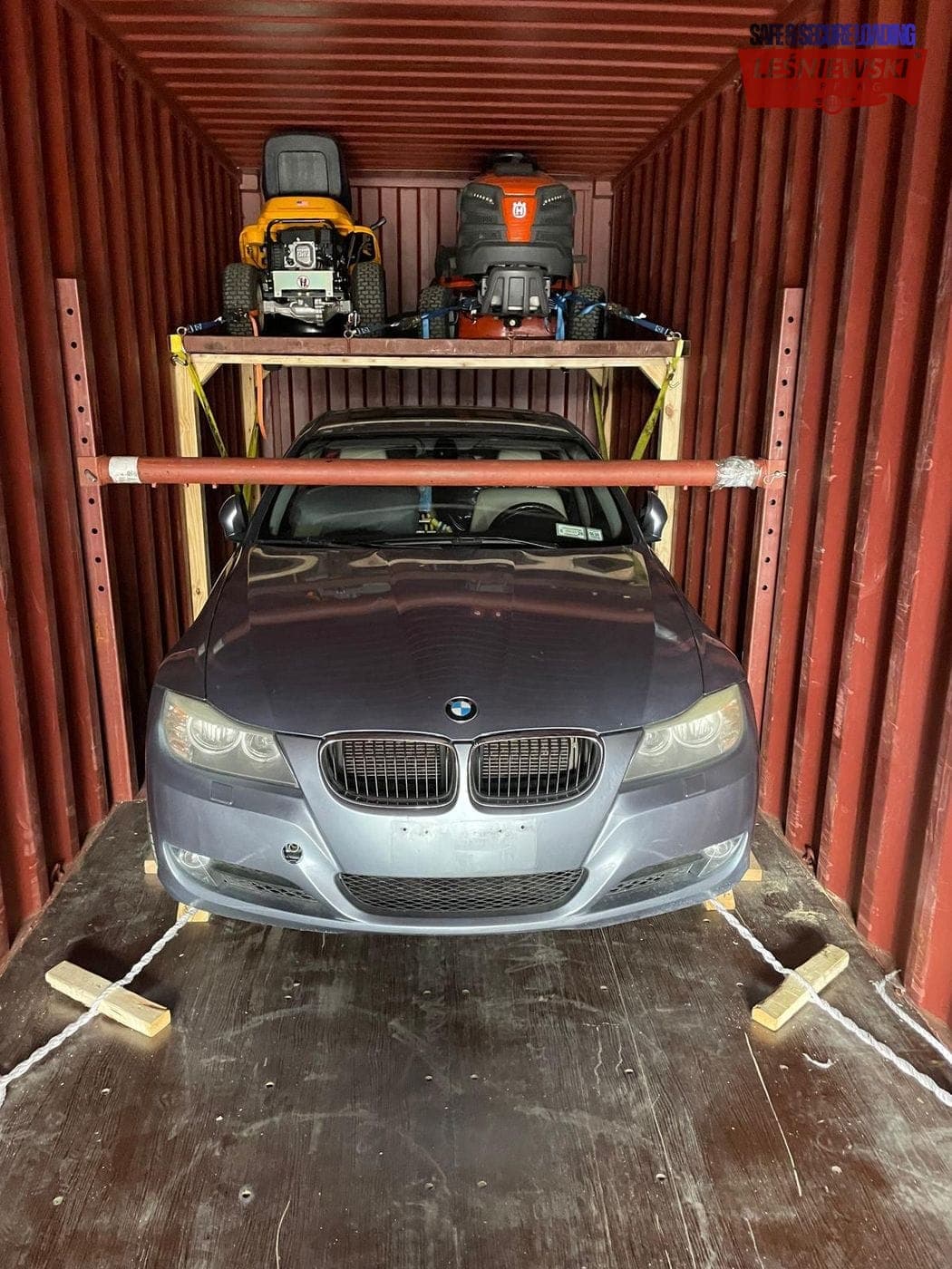 BMW 3 Series in a container with mowers on a rack — car transport from the USA